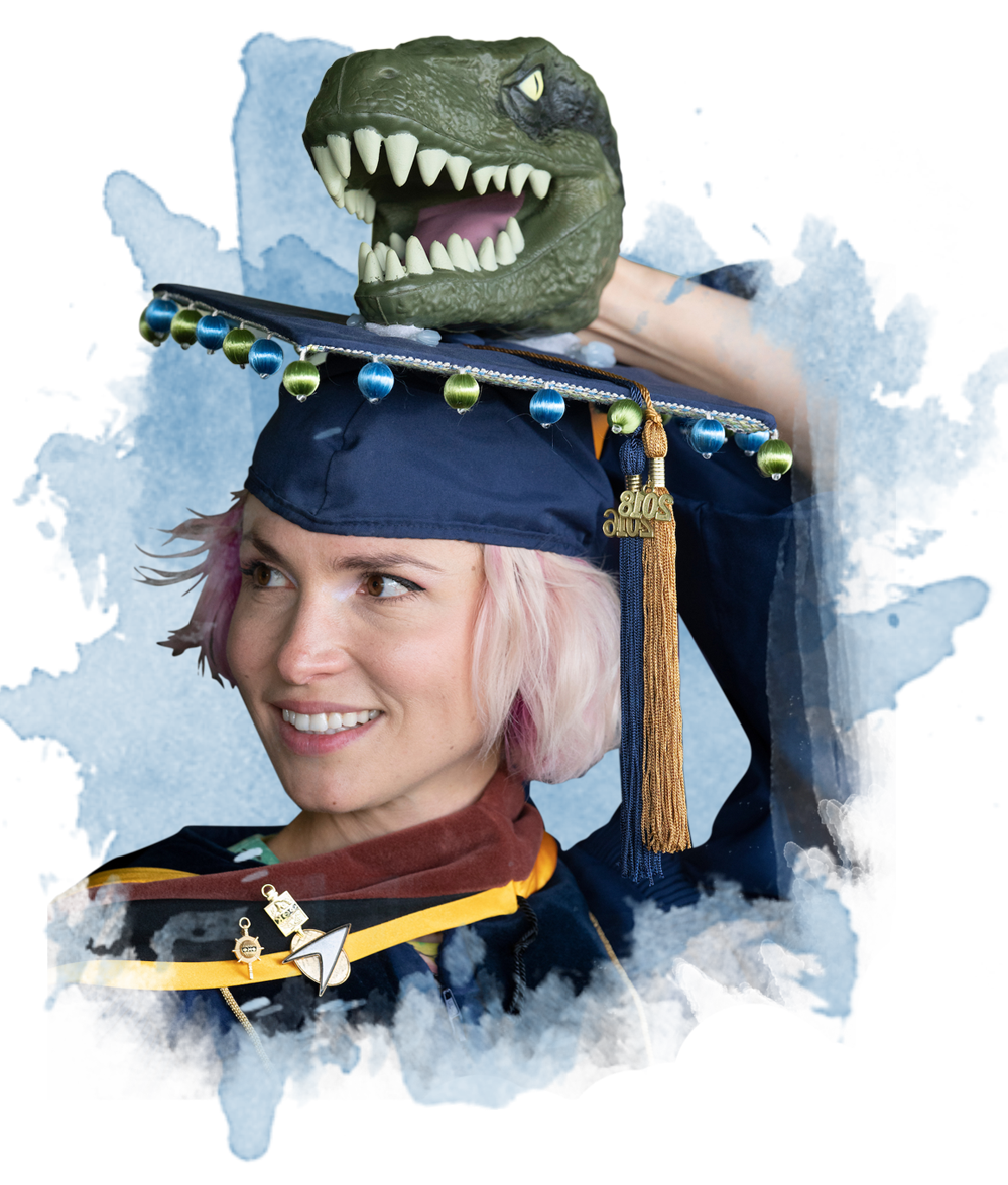 一个穿着毕业礼服的学生，毕业帽上有一个霸王龙的头