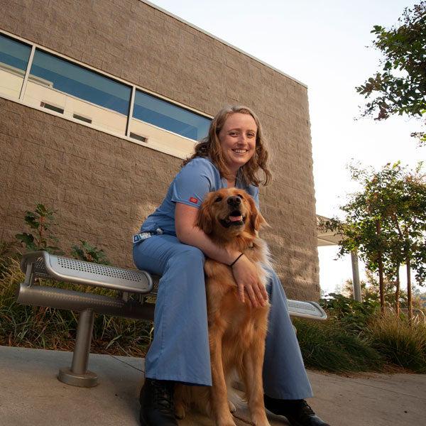 一名兽医专业的学生在澳门十大电子游戏大全兽医学院外照顾一只狗