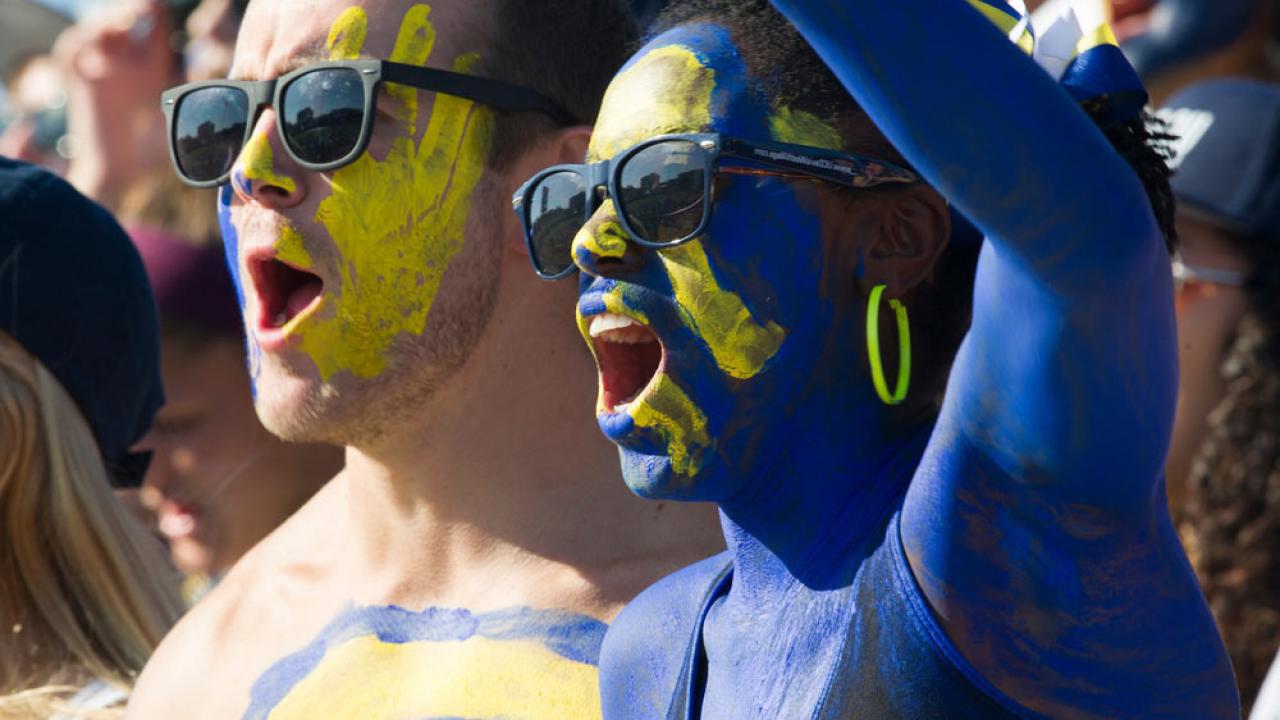在一年一度的返校橄榄球比赛上，一名男女学生被涂上了澳门十大电子游戏大全的蓝色和金色，为aggiies欢呼