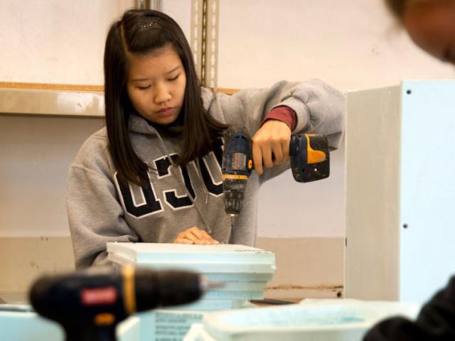 一名女学生在工艺中心使用电钻