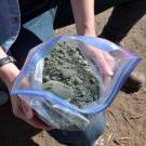 一个打开的塑料袋，里面装着被称为元玄武岩的碎灰色岩石. 研究人员发现，向农田中添加碳可以吸收空气中的碳.