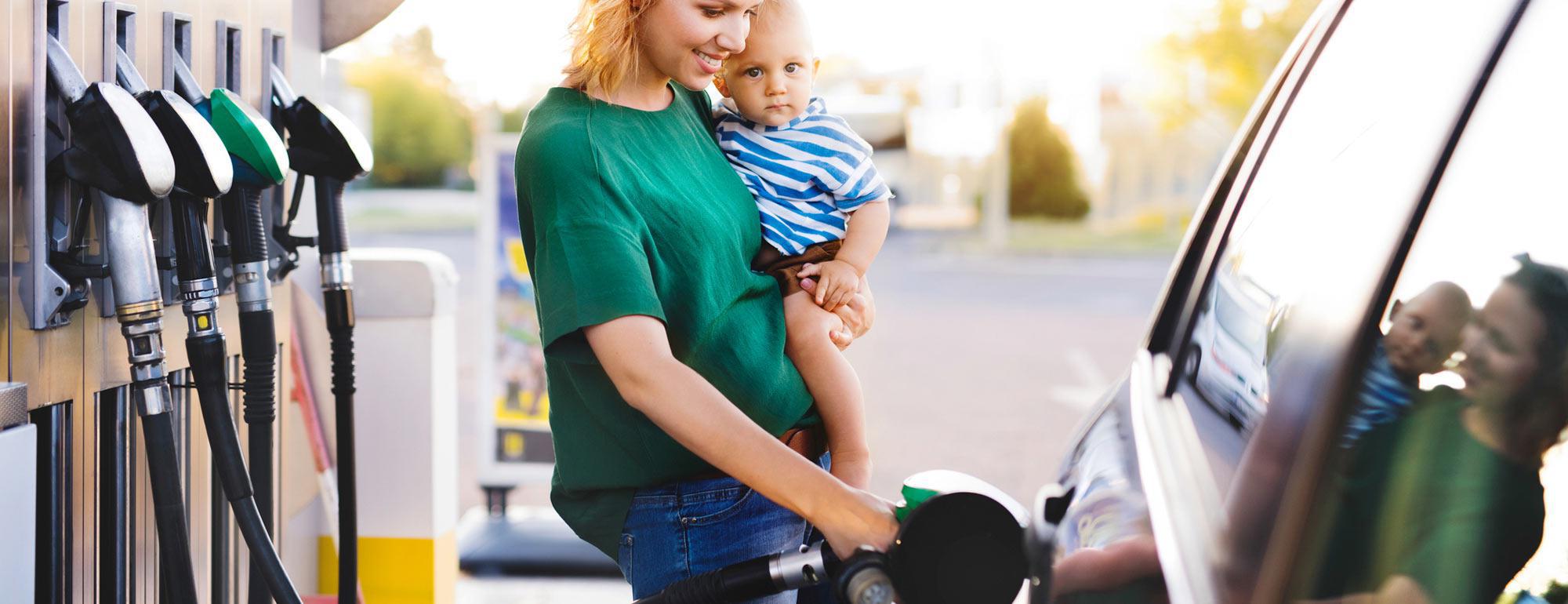 一位抱着婴儿的母亲在加油站给她的车加油