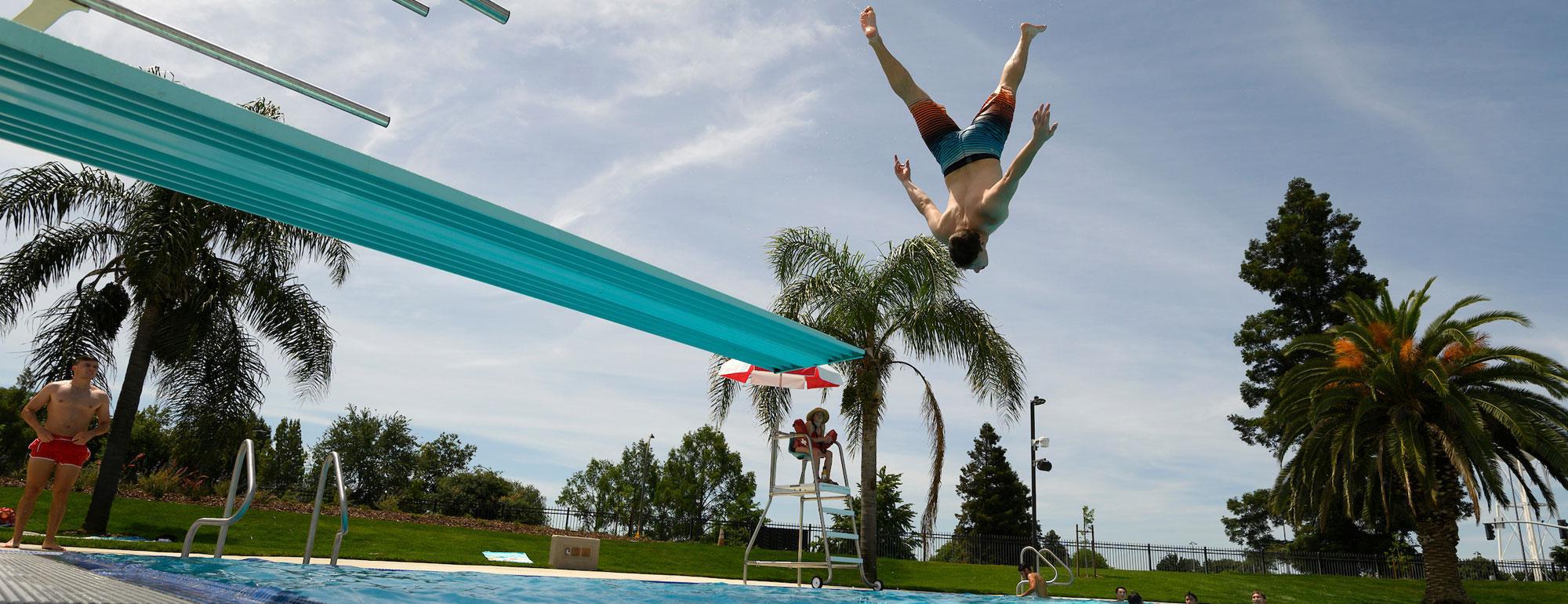 一名学生在加州大学戴维斯娱乐池的跳水板上做杂技跳跃